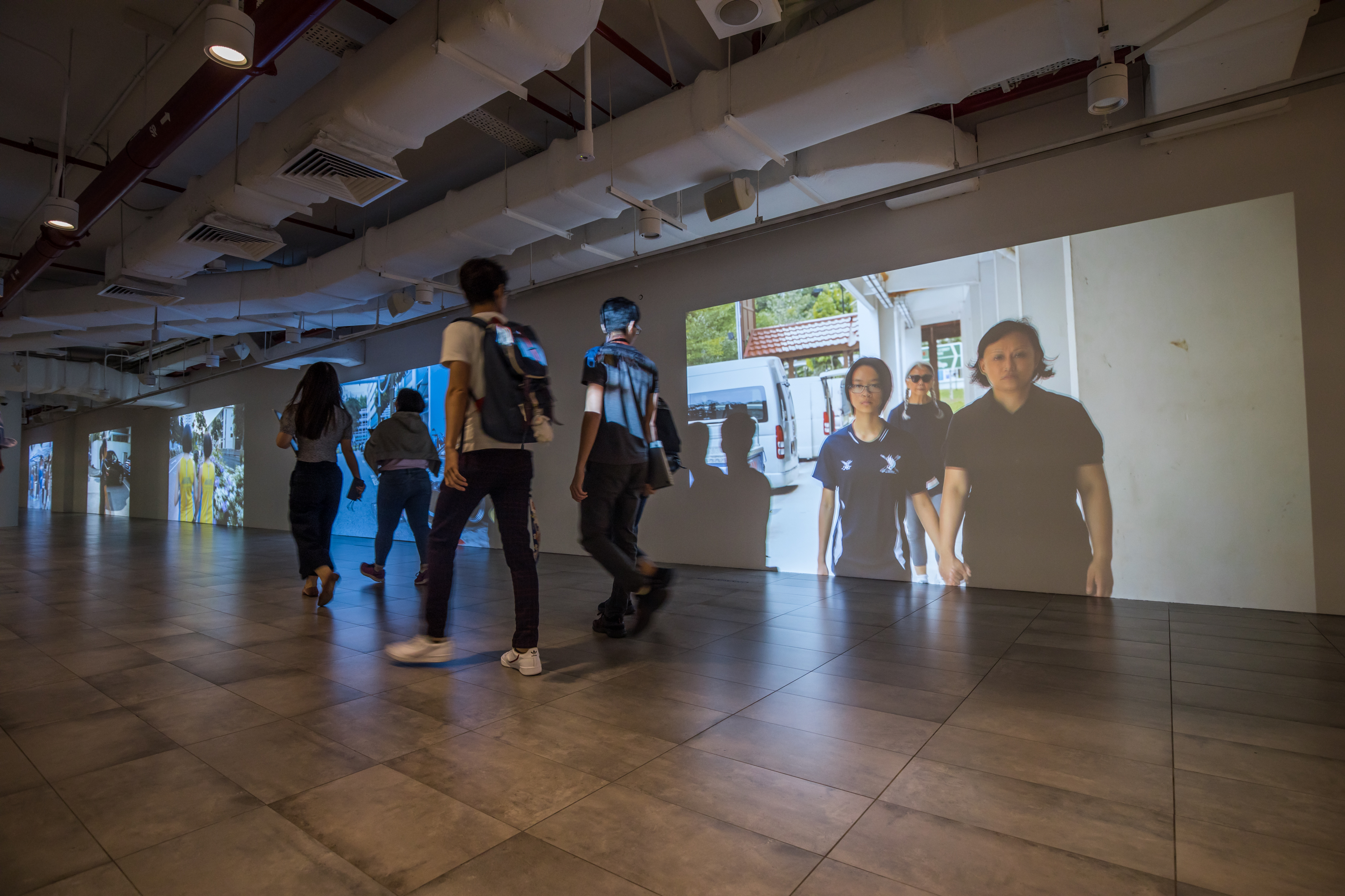 Passers-by looking at the video of Amanda Heng’s work projected onto the walls in the Esplanade tunnel.