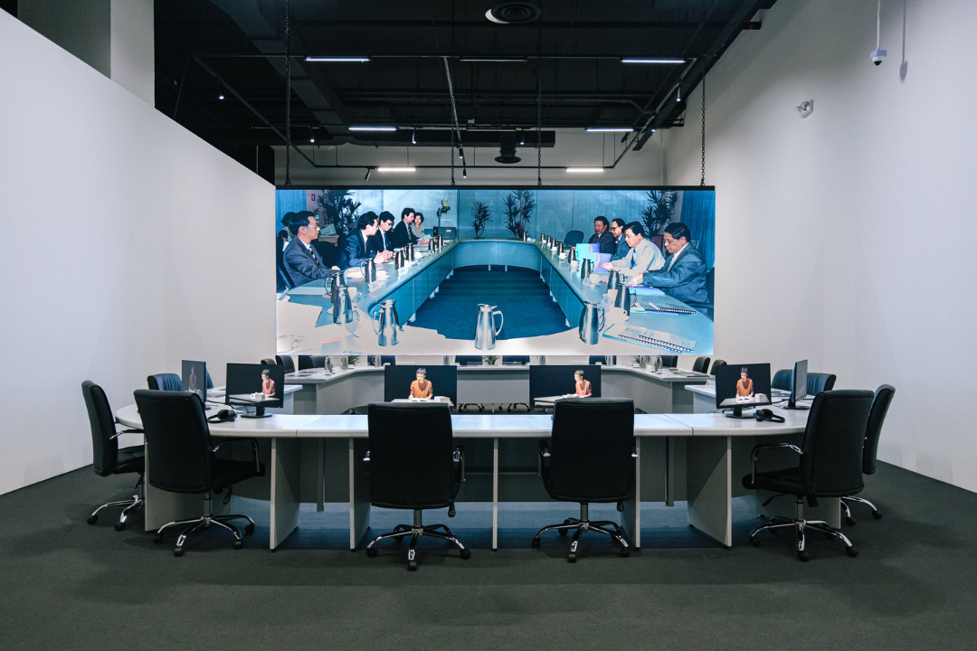 2021–22. Lecture and video installation with digital prints on paper, conference table, office chairs, desk, stool, book trolley, books, thermos flasks, cups, saucers and acrylic name plate holders. Installation view, 'Lonely Vectors', Singapore Art Museum, 2022 Courtesy of Singapore Art Museum