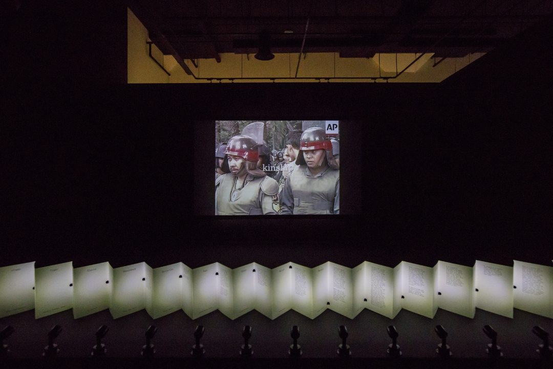  Ho Tzu Nyen, 'CDOSEA (The Critical Dictionary of Southeast Asia)', 2017–ongoing. Algorithmically composed video, infinite loop, configurations variable. Installation view at 'Ho Tzu Nyen: Time & the Tiger', SAM at Tanjong Pagar Distripark, 24 Nov 2023‒3 Mar 2024. Foreground: Ho Tzu Nyen, 'F for Fold (The Critical Dictionary of Southeast Asia)', 2021. Artist’s book. Image courtesy of Singapore Art Museum.