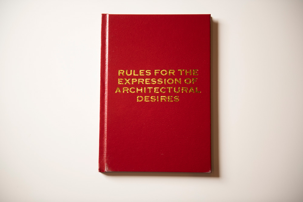 Debbie Ding. 'Rules for the Expression of Architectural Desires.' 2014–2021. 24 UV printed posters; 3 browsing copies of Rules for the Expression of Architectural Desires; 3 specially designed stools that observe strict social distancing; and two videos, single-channel, 16:19 format, colour and sound (stereo), 8 min. Dimensions variable. Collection of Singapore Art Museum. Image courtesy of Singapore Art Museum.